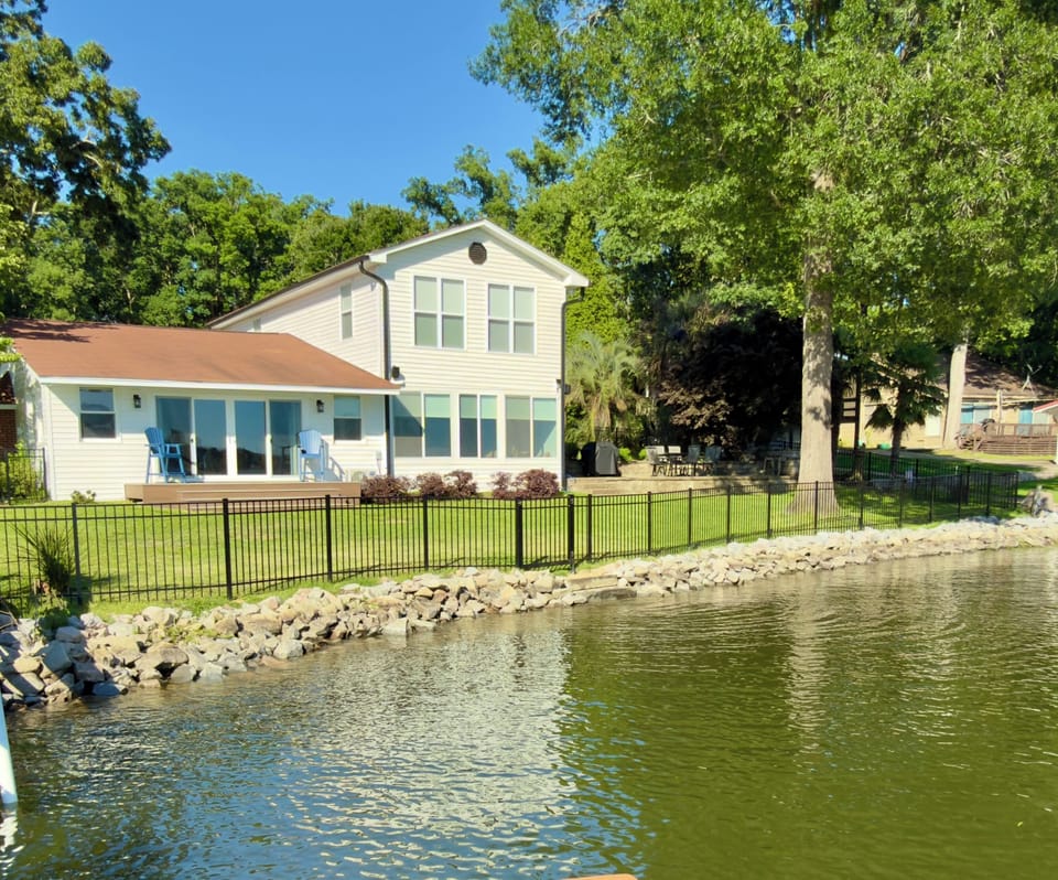 Spacious waterfront home with fenced yard, patio, and serene lake views