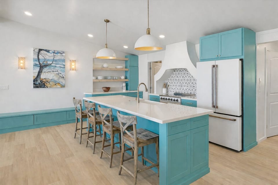 Whip up memorable meals in this stunning coastal kitchen featuring turquoise cabinets, white quartz counters, and a spacious island perfect for gathering.