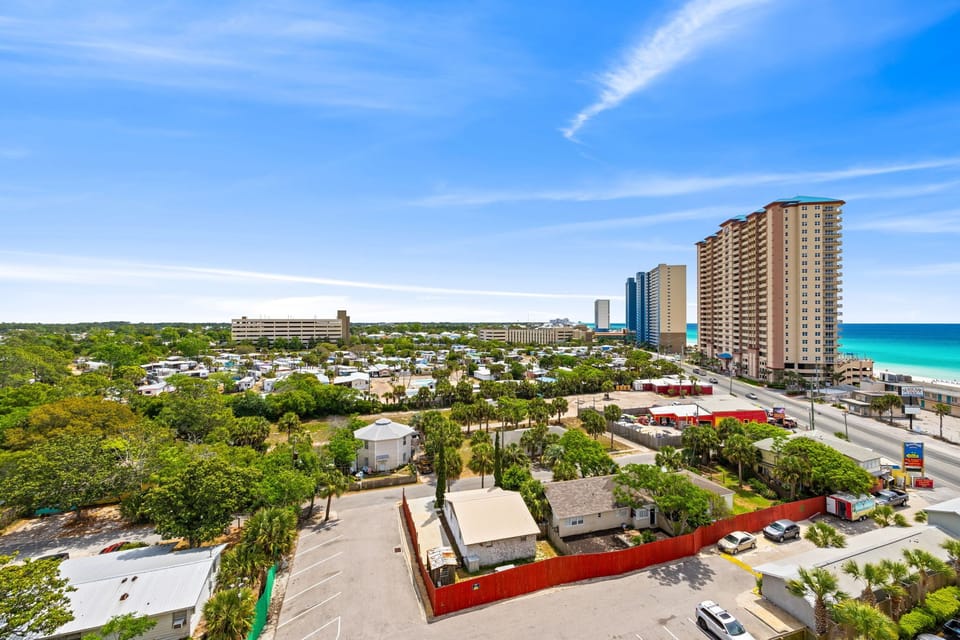 Aerial view of the beachfront neighborhood featuring coastal residential community with high-rise buildings and pristine turquoise waters nearby.