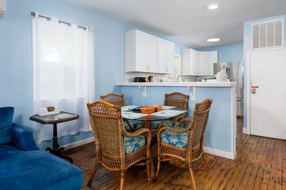 Gather around the coastal-style dining table where your meals become memories, with a fully-equipped kitchen at your fingertips and bright blue walls creating a breezy, beachy atmosphere.