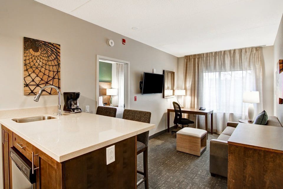 Two-seat kitchen bar looks out over the suite — a quick spot for morning coffee before the free breakfast starts downstairs.