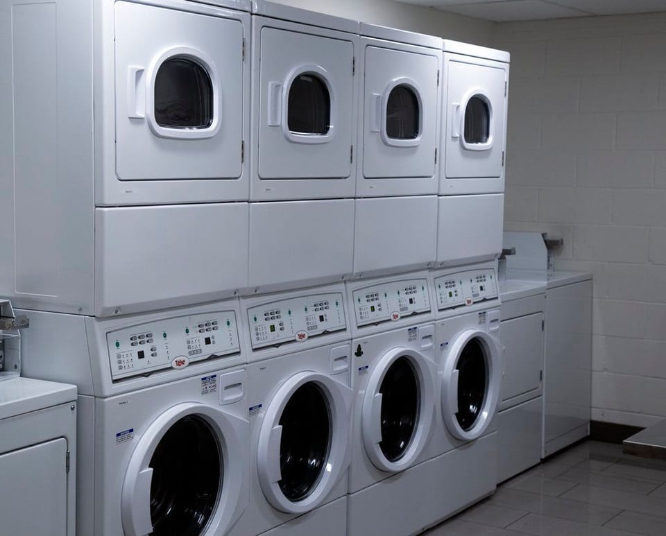 Stacked washers and dryers with digital displays in the self-service laundry room.