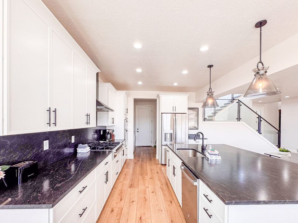 Sleek kitchen with gas range, double ovens, island sink, and clean modern finishes