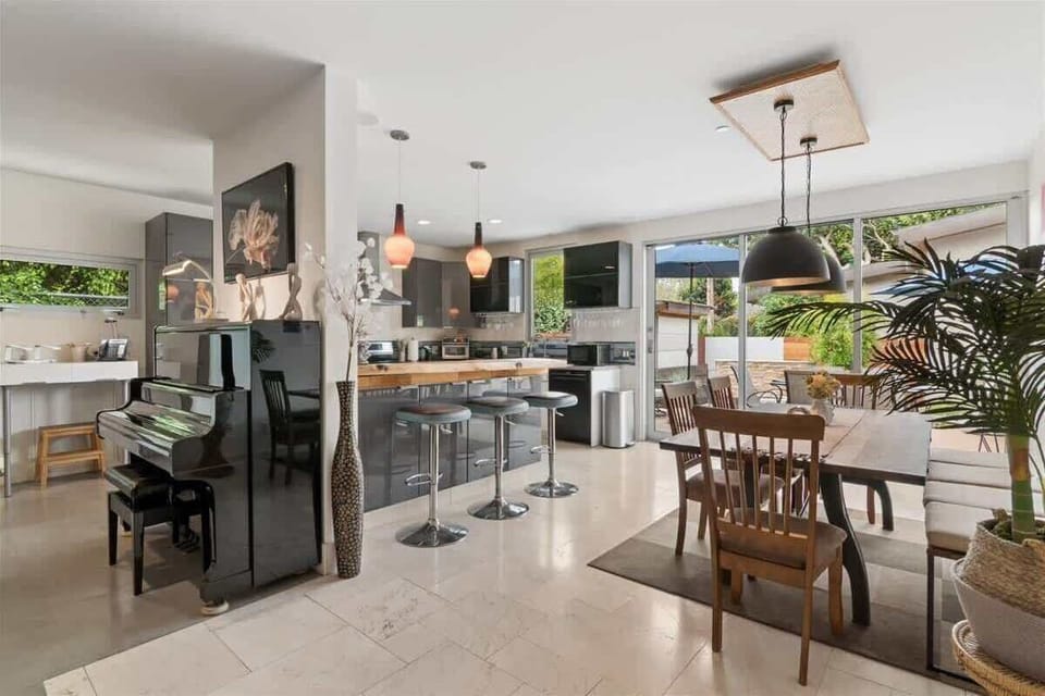 Open indoor-outdoor feel from the back deck to the dining room, with plenty of seating and a beautiful piano to match.