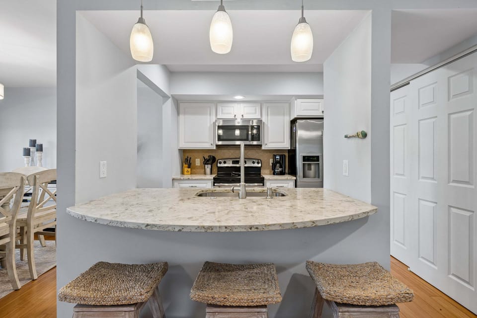 Fully stocked kitchen featuring all stainless steel appliances and 3 barstools for extra seating.