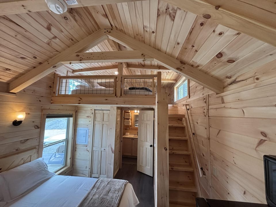 Cozy loft bedroom with vaulted pine ceilings and natural light