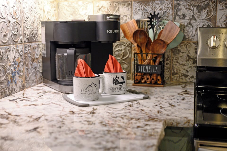 Wake up to your perfect morning brew with the Keurig coffee maker, complete with charming cabin-themed mugs ready for your first sip.