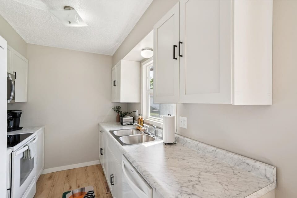 Kitchen | Unit 1 | Main Floor
Full kitchen with double-basin sink, electric range and oven, microwave, and full-size refrigerator. Counter space for food preparation and upper and lower cabinet storage. Window above the sink.