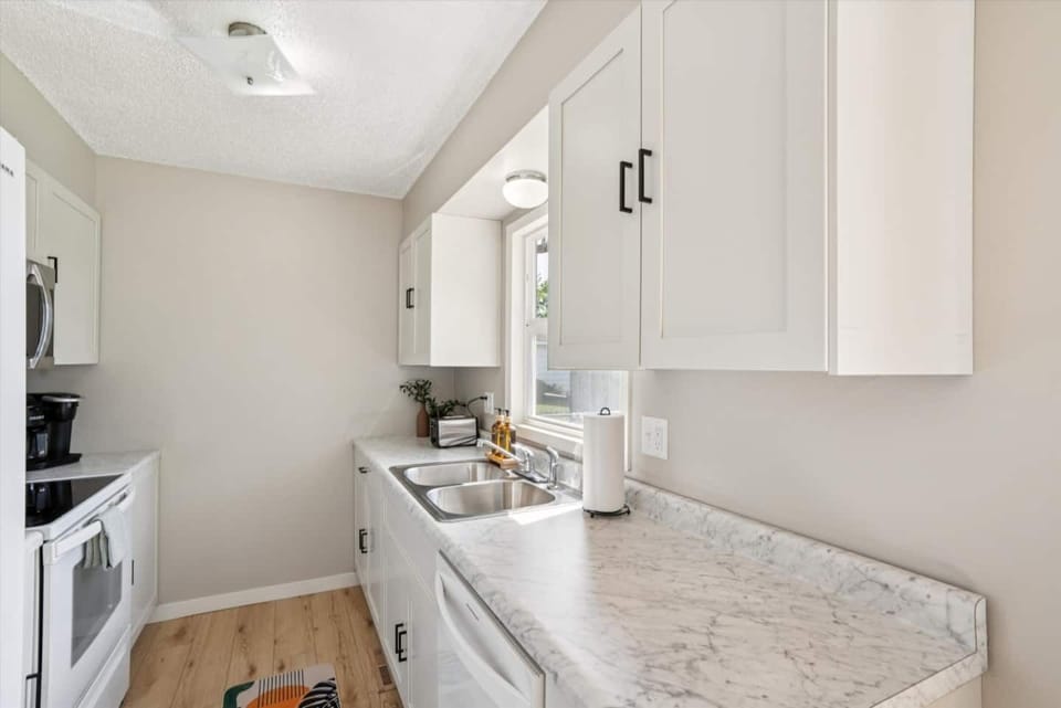 Kitchen | Unit 1 | Main Floor
Full kitchen with double-basin sink, electric range and oven, microwave, and full-size refrigerator. Counter space for food preparation and upper and lower cabinet storage. Window above the sink.