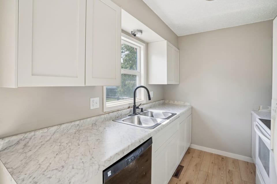 Kitchen | Unit 2 | Main Floor
Full kitchen with double-basin sink, dishwasher, electric range and oven, microwave, and full-size refrigerator. Counter space for food preparation and cabinet storage. Window above the sink.