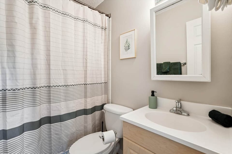 Full Bathroom | Unit 2 | Upper Floor
Shared full bathroom with single-sink vanity, mirror, and storage cabinet below the sink. Toilet and tub/shower combination. Accessible from the upper-floor hallway and shared by multiple bedrooms.