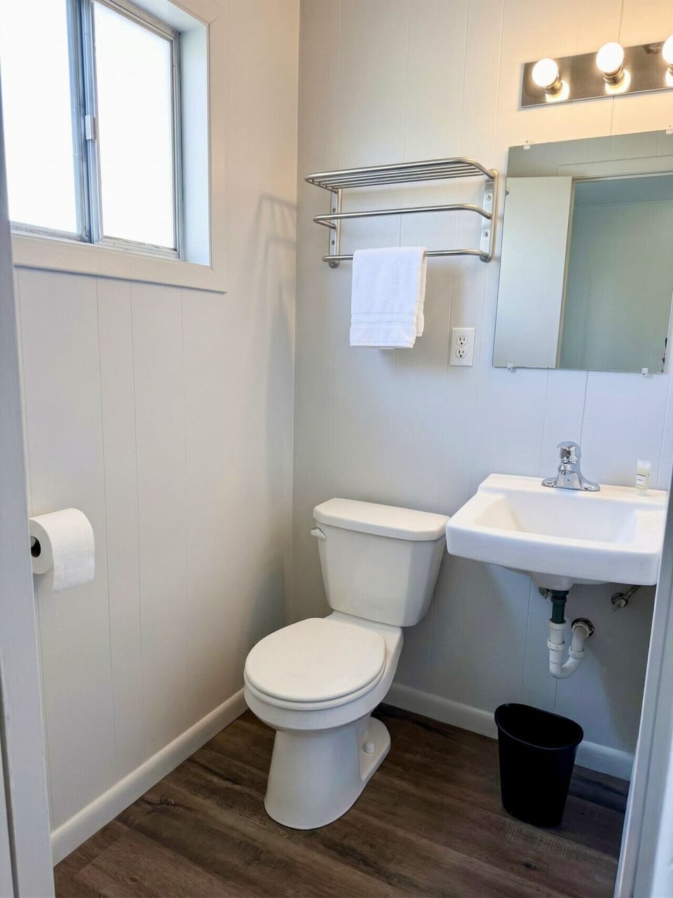 Private bathroom with clean white fixtures, wall-mounted sink, and fresh towels