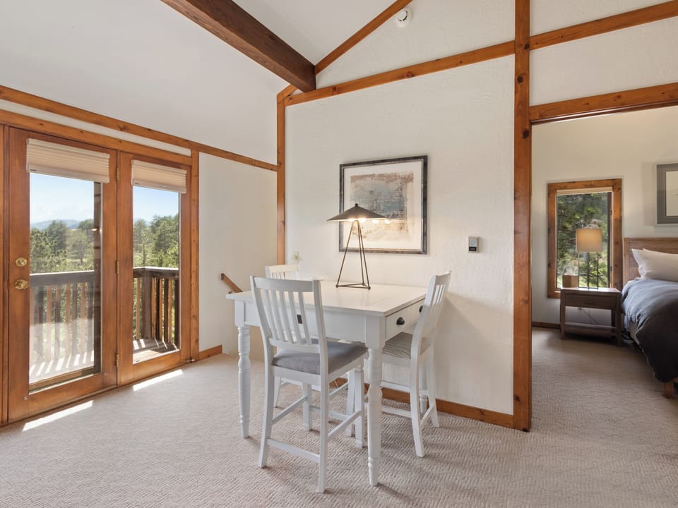 A cozy game space where warm wood beams frame peaceful mountain views through your private balcony doors.