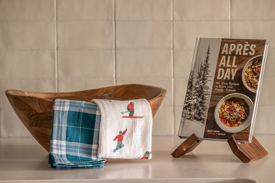 Your mountain retreat kitchen awaits with thoughtful touches—rustic wooden bowl, cozy ski-themed linens, and après-ski recipe inspiration for memorable evenings.