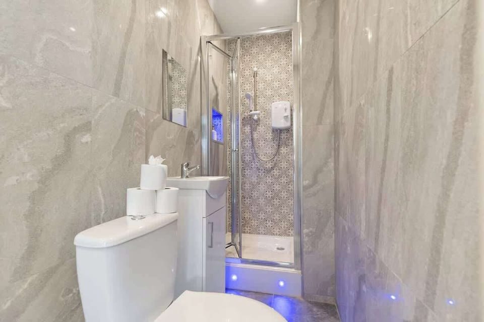 Modern bathroom featuring a sleek walk-in shower with rainfall head, contemporary tiling, and stylish vanity. Finished with ambient lighting and fresh towels, creating a clean, relaxing space to refresh and unwind.