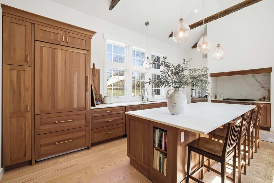The panel-integrated refrigerator and floor-to-ceiling walnut cabinetry keep the kitchen feeling cohesive and uncluttered from every angle.