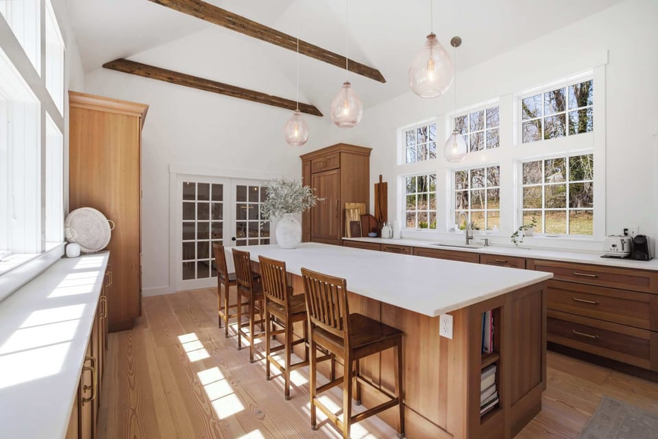 The island seats four and the timber beams overhead have been here for centuries — this is a kitchen that earns its place as the center of the house.