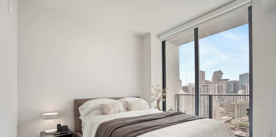 Comfortable queen bed with large city-view windows
