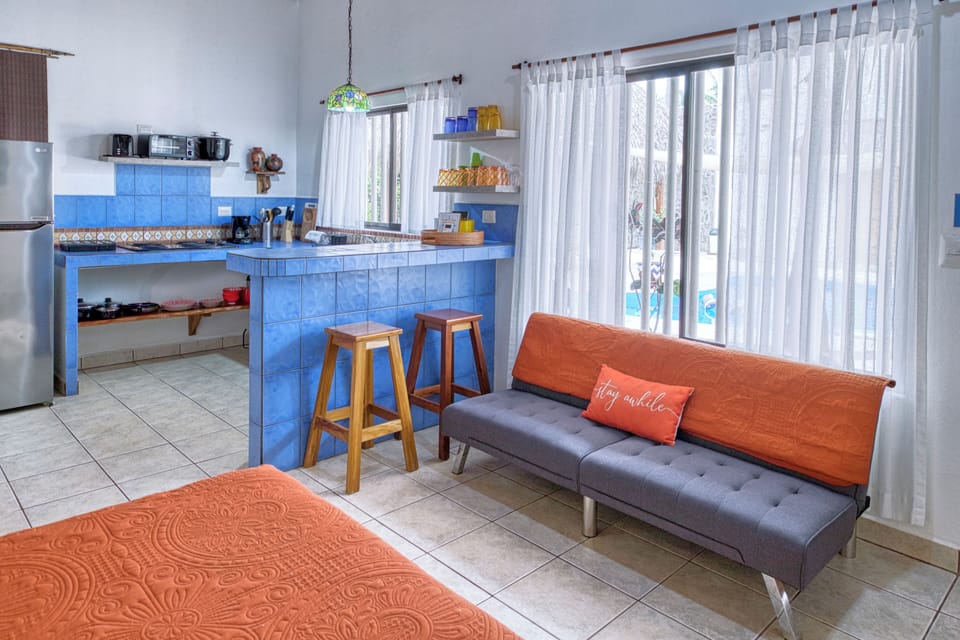 Bright studio: vibrant blue tile kitchen, cozy seating, and a relaxing tropical 