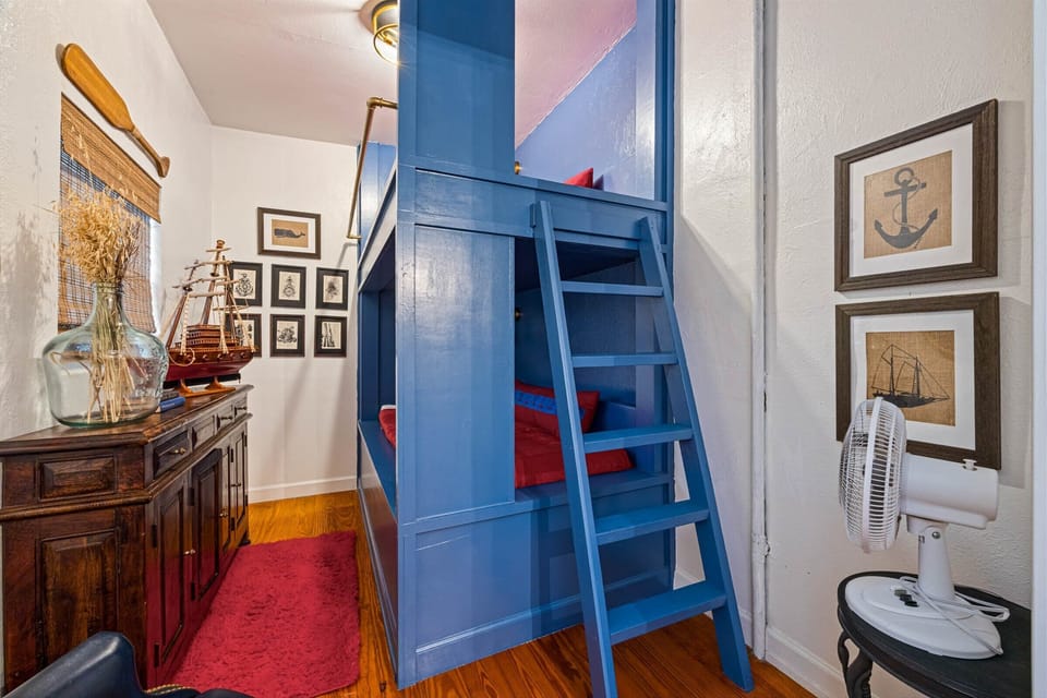 Unique bunk room with built-in blue bunk beds, ladder access, and playful coastal design.