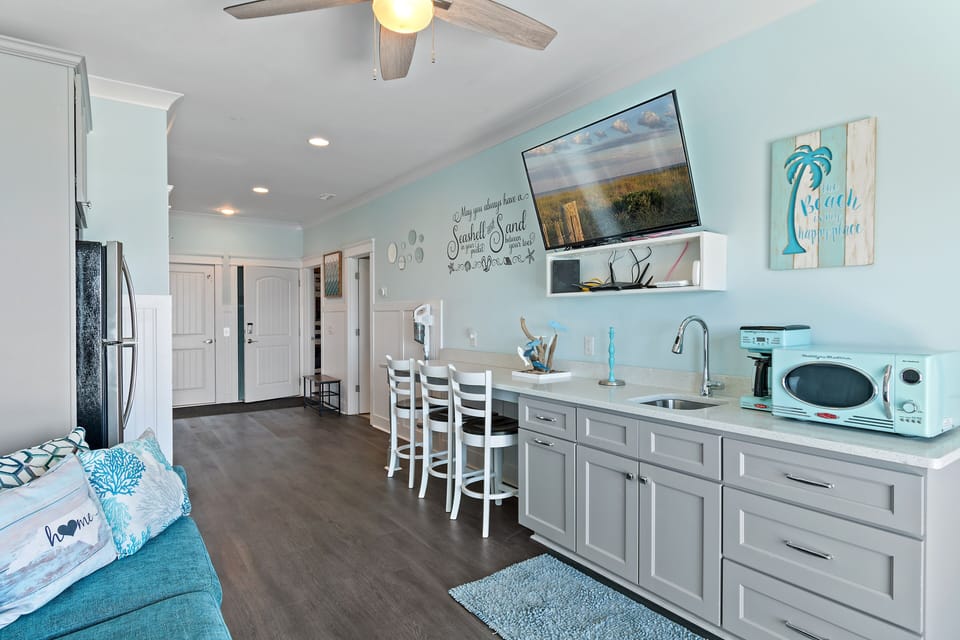 Convenient kitchenette with sink, mini-fridge, and storage — ideal for prepping drinks and snacks before heading to the pool or beach.