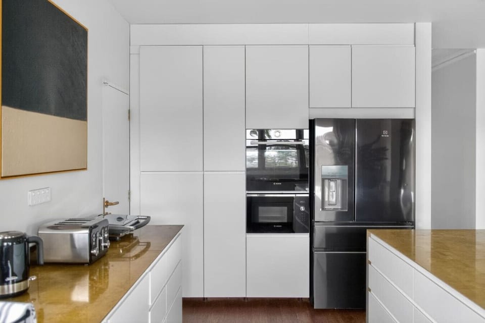 Fully equipped kitchen featuring a large fridge, built-in microwave, oven, sandwich press, toaster, and kettle -everything you need for easy, everyday cooking.
