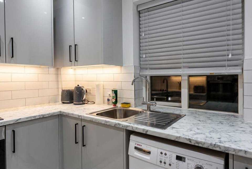 Marble worktop kitchen with under-cabinet lighting, kettle, and Bosch dishwasher ready for home-cooked meals.