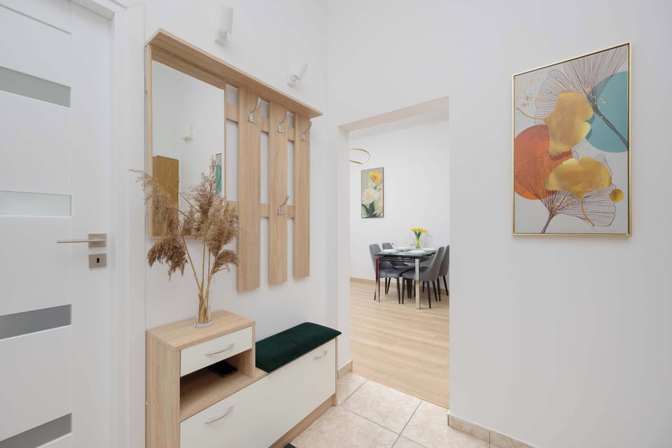 A bright hallway with a large wardrobe featuring mirrored doors that visually enlarge the space. A simple bench and light decor create a welcoming and functional entry area.