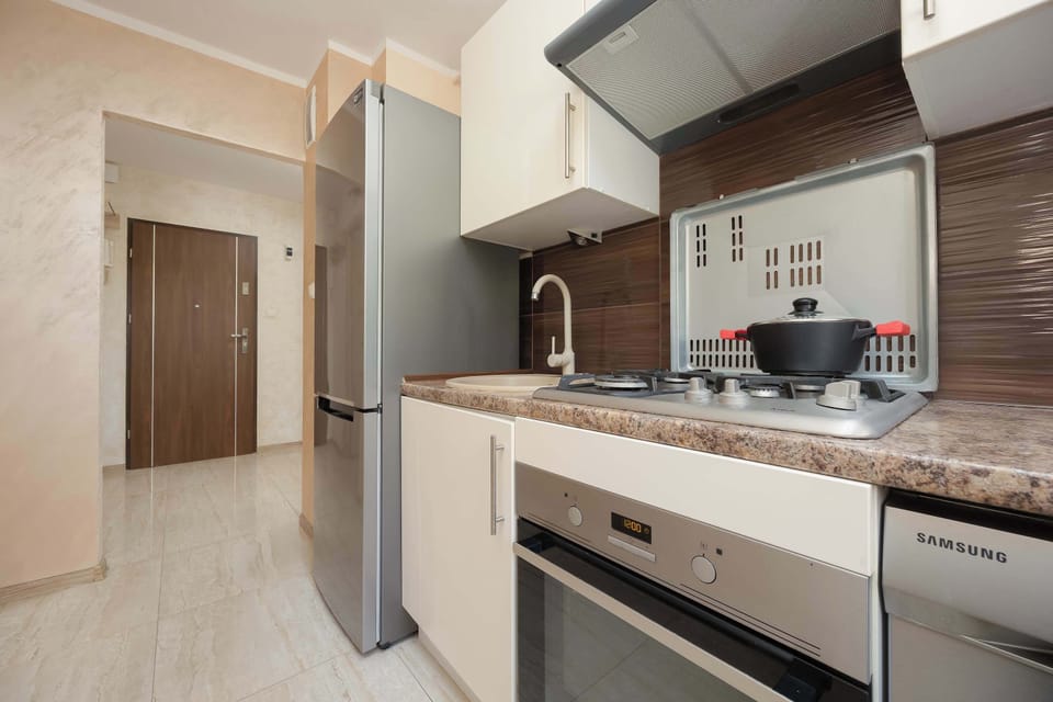 The entrance hallway leads directly into the kitchen, showing a modern silver refrigerator. Light-colored flooring runs throughout the space, connecting the different zones.
