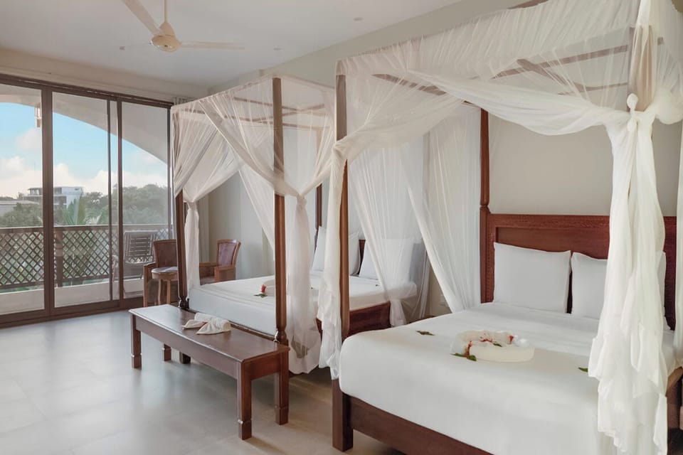Wake up in breezy canopy beds beside a sunny balcony.