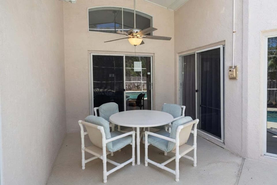 Shaded covered patio with a round dining table, seating for 4–6, and ceiling fan. Ideal for relaxing outdoors while staying protected from the sun.