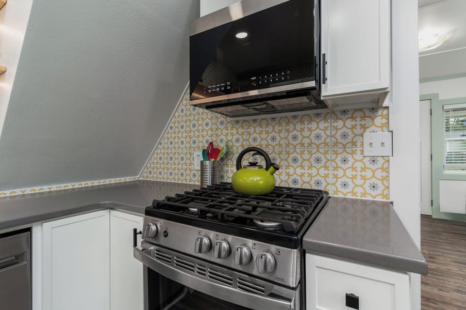 Cook your favorite meals on this modern gas stove with a vibrant kettle ready for your morning coffee ritual.