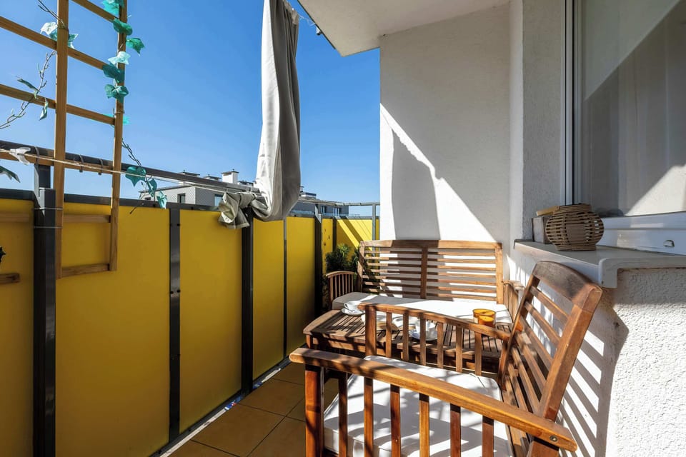 A balcony with wooden seating and a table, enclosed by bright yellow panels.
