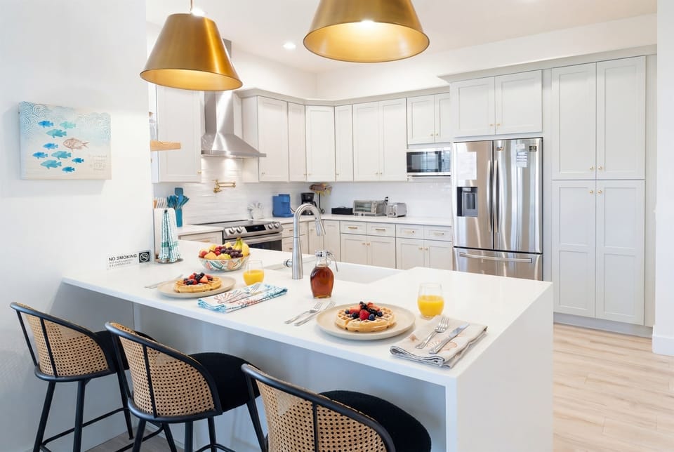 Fully equipped modern kitchen with large island, bar seating, stainless steel appliances, and quartz countertops — Palm Coast, FL vacation rental perfect for families and group stays.