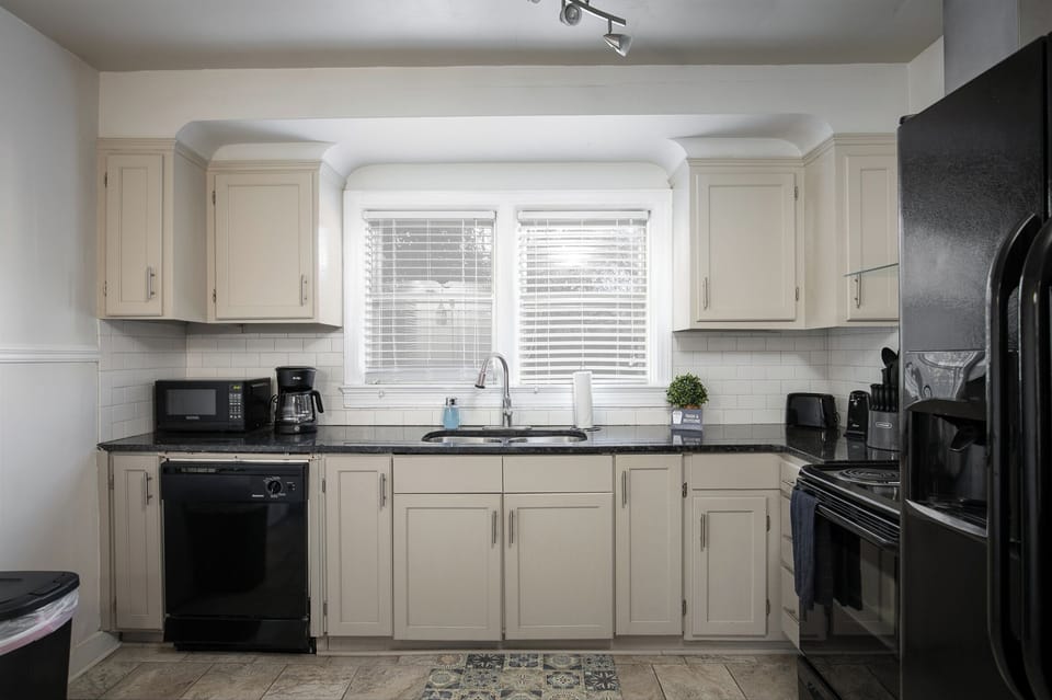 Step into the bright, fully stocked kitchen with light cabinetry and sleek black appliances, ready for anything from quick breakfasts to full meals
