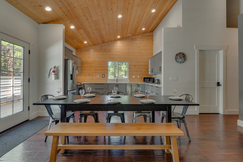 Rustic dining area w/ bench seating, vaulted ceilings & open sightlines to the kitchen