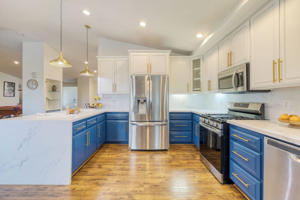 Bright, modern kitchen with bold blue cabinetry, gold accents, and a spacious island for gathering. (Main House)