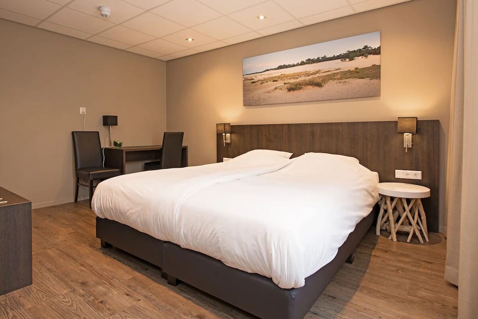 Sink into a spacious bed under warm lighting and serene decor.