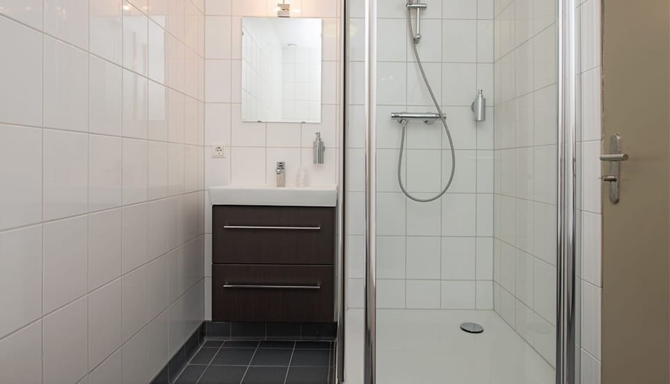 Rinse off in a spotless walk-in shower with bright tilework.