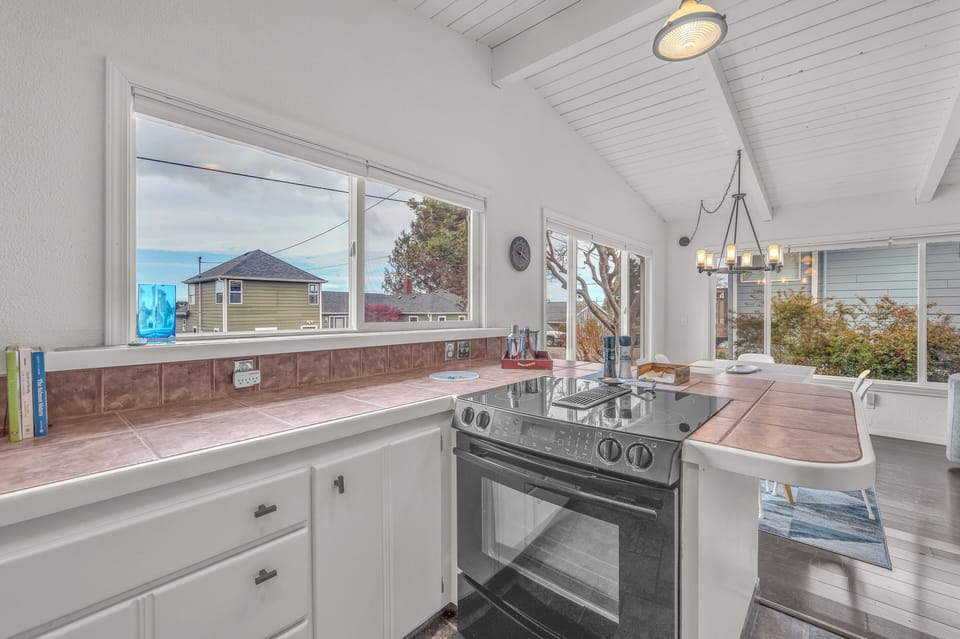You'll love cooking in this bright, airy kitchen with its charming white beadboard ceiling, warm tile counters, and inspiring neighborhood views through large windows.