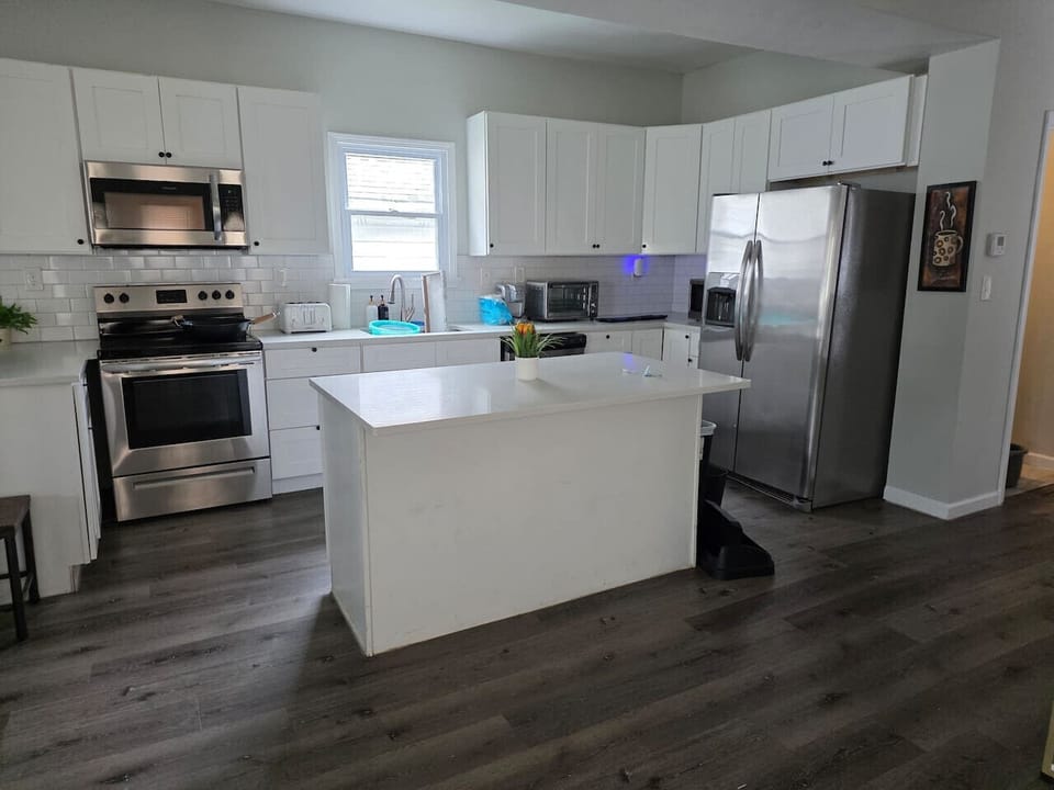 Step into a modern and fully equipped kitchen featuring crisp white cabinetry and a matching subway tile backsplash that brightens the entire culinary space. The kitchen is outfitted with high-end stainless steel appliances, including a full-sized refrige