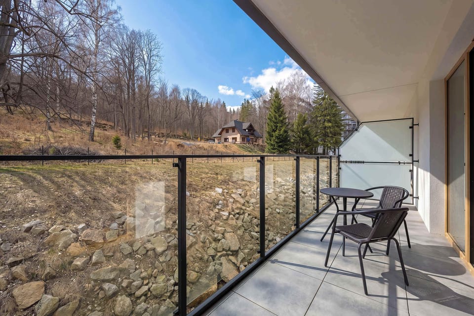 A wide balcony view overlooking a forested area. The outdoor space is peaceful and scenic.