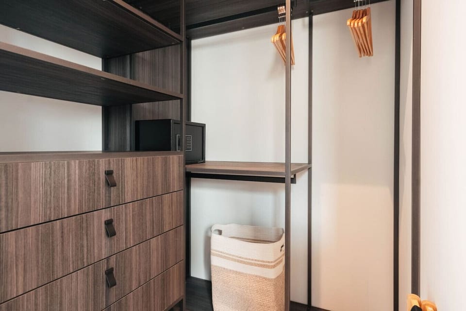 Detailed shot of the master closet organizer at Palm Beach Villas in Runaway Bay, Jamaica, showing wooden drawers, clothing rods, and an integrated digital safe.