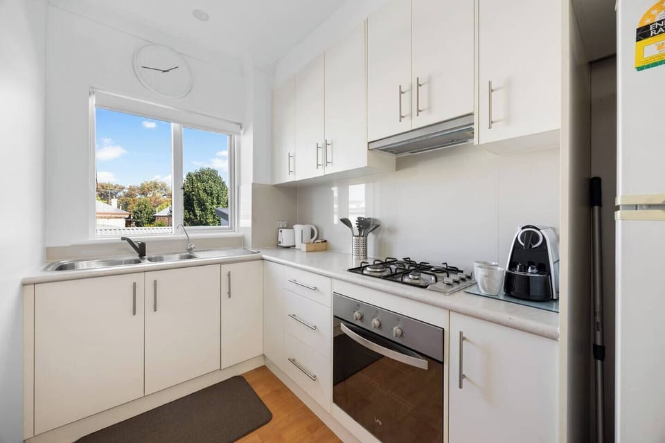 A bright, well-equipped kitchen where you can easily prepare meals, with ample storage, modern appliances, and a sunlit window bringing in plenty of natural light.