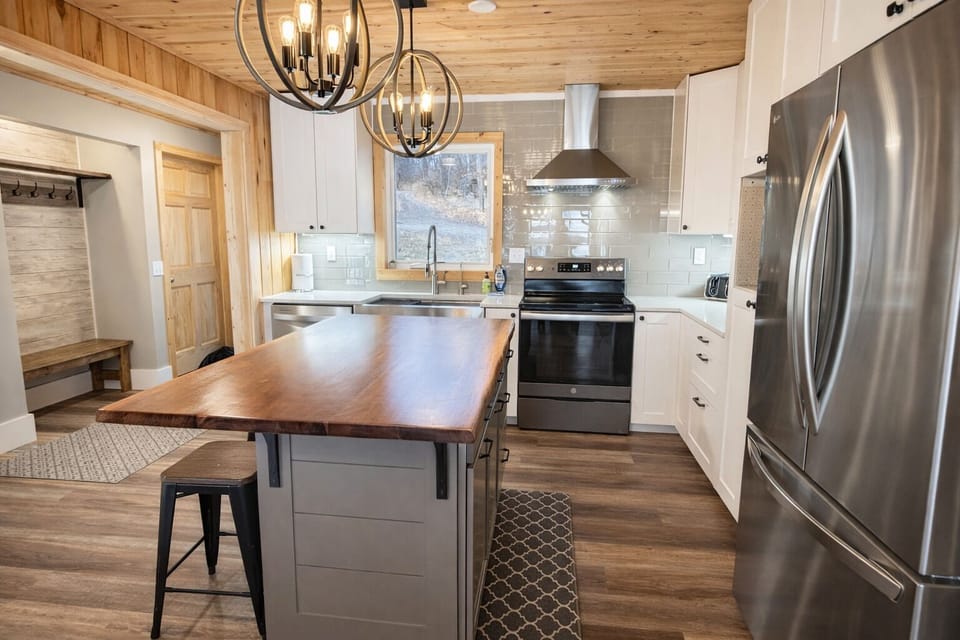 Bright, modern kitchen with stainless steel appliances, updated finishes, and great lighting, flowing into the inviting living room with beautiful lake views through the windows. A stylish, open gathering space designed for connection and comfort.