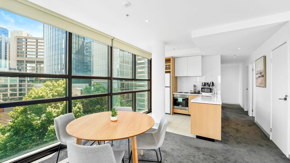 Sunny dining space by the windows—perfect for morning coffee while enjoying leafy outlooks and city glimpses.