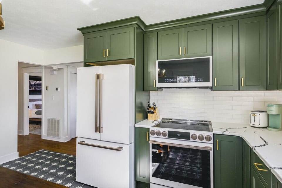 Fully equipped kitchen with full-size appliances, stylish olive cabinetry, cookware, and everything needed for home-cooked meals.