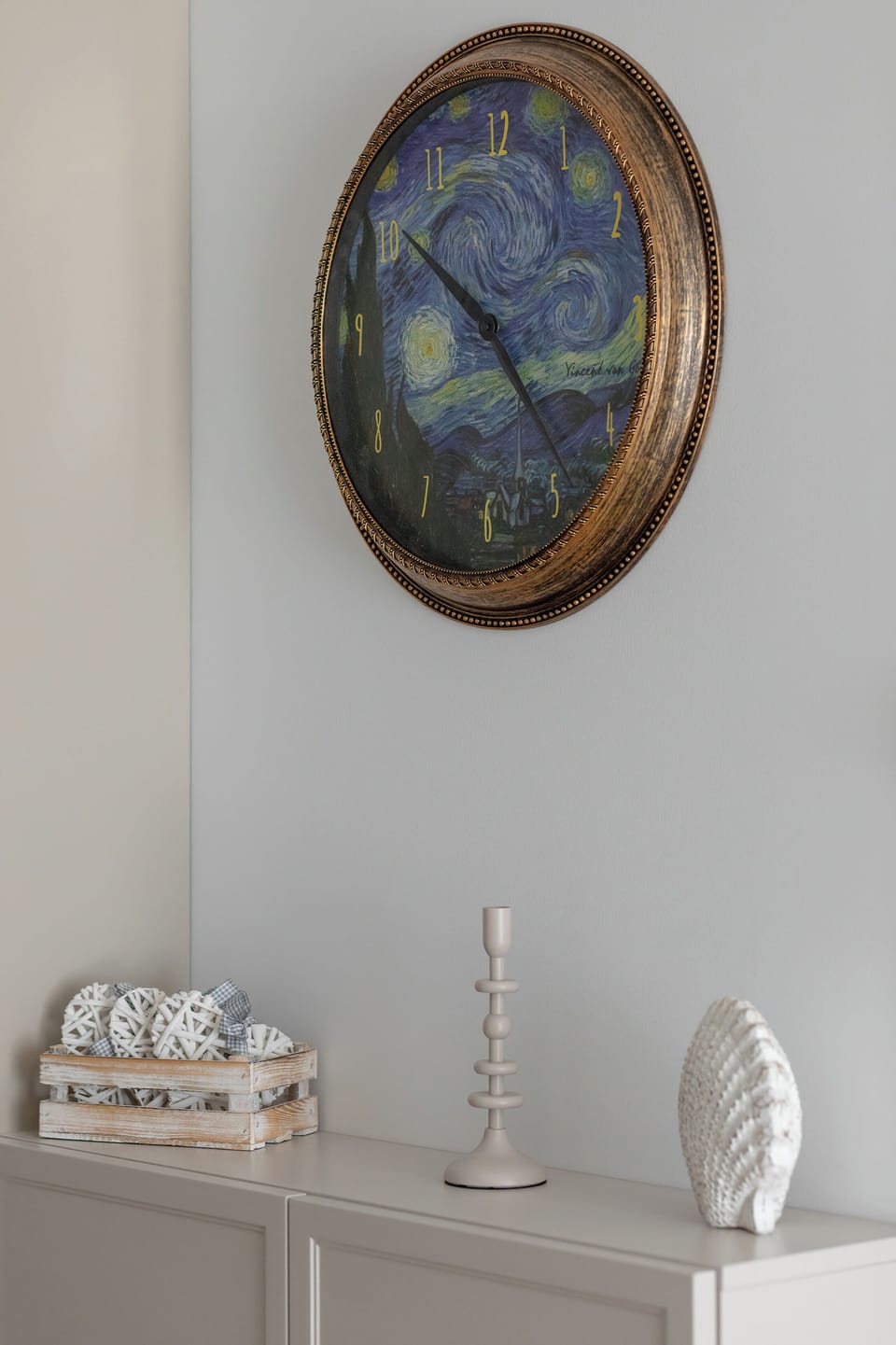 A decorative wall detail featuring a round mirror and small ornamental items on a shelf. Neutral tones give a refined look.