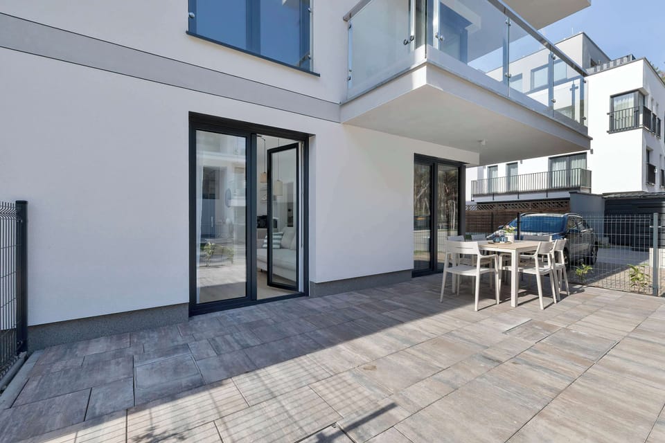 A spacious outdoor patio with a dining set and modern building exterior. The area is ideal for relaxing or entertaining.