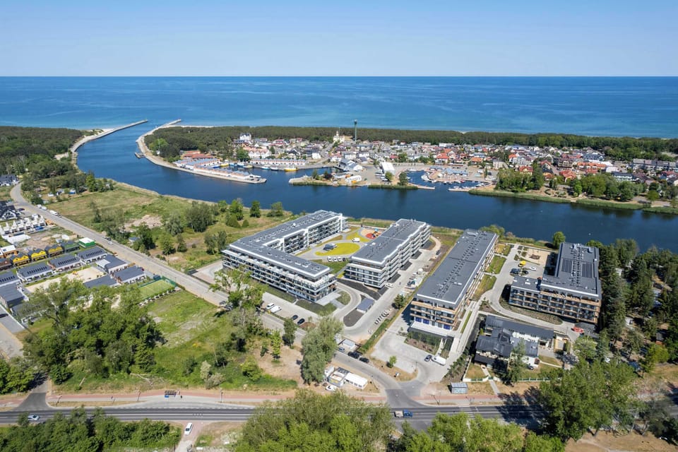 A high-angle view of a coastal town with buildings, roads, and surrounding water.

